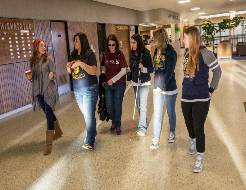 Group of students walking down hallway in campus commons building.